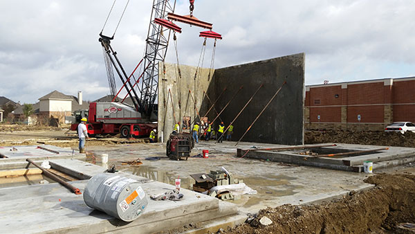 Image of workers and a crane installing two walls of a new commercial building